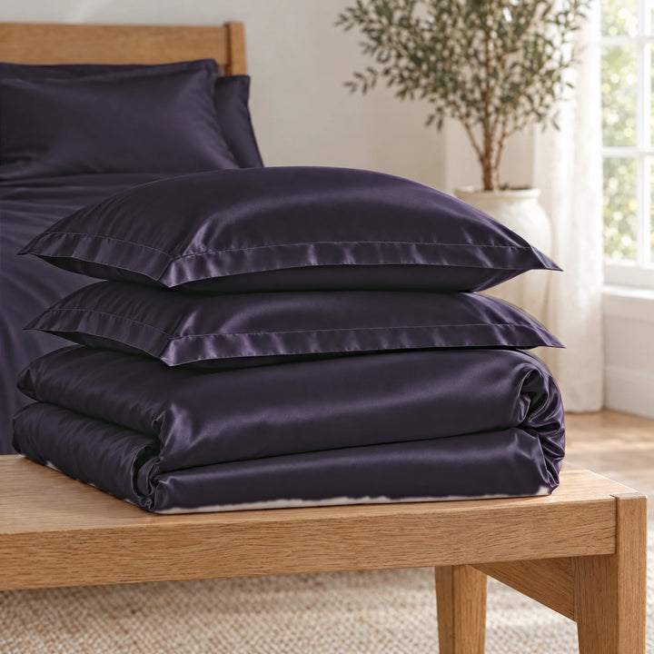 Royal Purple bamboo viscose Signature duvet cover and two shams, neatly folded in a stack on an oak bench