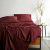 ruby red bamboo bed sheets with sateen weave from the Signature Collection, shown from the foot of the bed with a draped flat sheet and matching pillowcases
