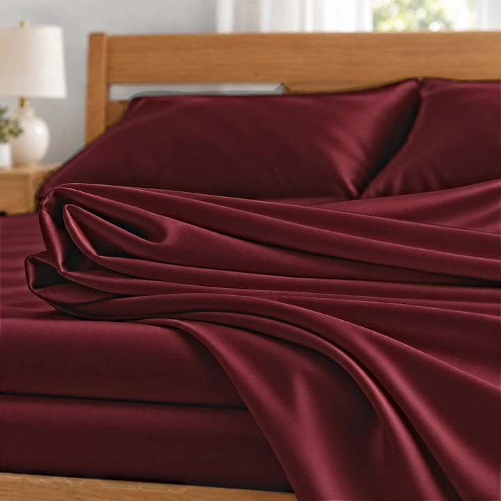 Ruby Red bamboo viscose sateen fabric close-up of folded sheets and a body pillowcase, silky sateen finish