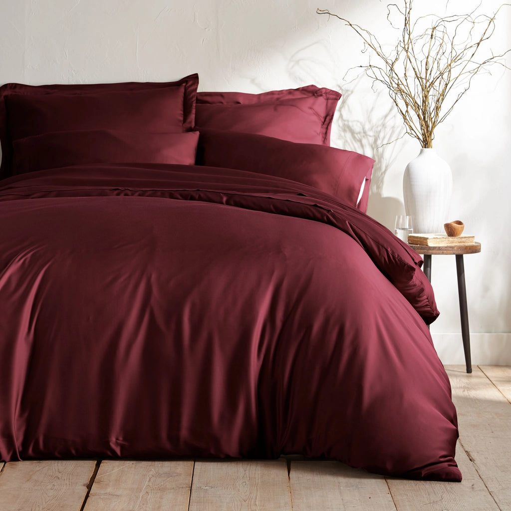 ruby red bamboo bed sheets with sateen weave from the Signature Collection, shown foot view with matching pillowcases and a modern nightstand