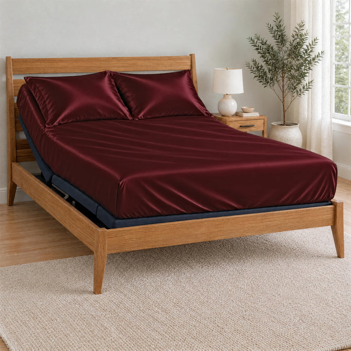 Ruby Red bamboo viscose Signature fitted sheet on a made bed with a bamboo frame and nightstand in a bright bedroom