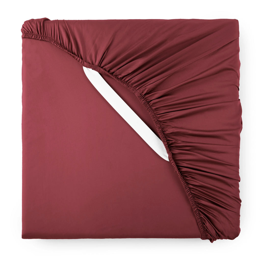 ruby red bamboo sateen fitted sheet corner with ruby red elastic strap, showing snug fit and smooth fabric texture