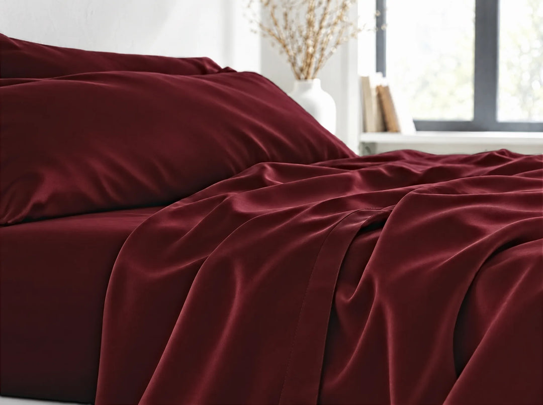 Ruby Red bamboo viscose flat sheet close-up billowing over the mattress edge in relaxed sateen folds