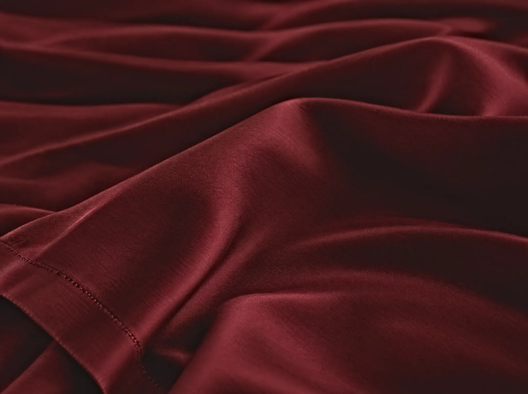 Ruby Red bamboo viscose flat sheet macro close-up of smooth silky sateen folds and a stitched hem