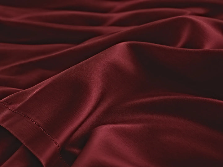 Ruby Red bamboo viscose flat sheet macro close-up of smooth silky sateen folds and a stitched hem