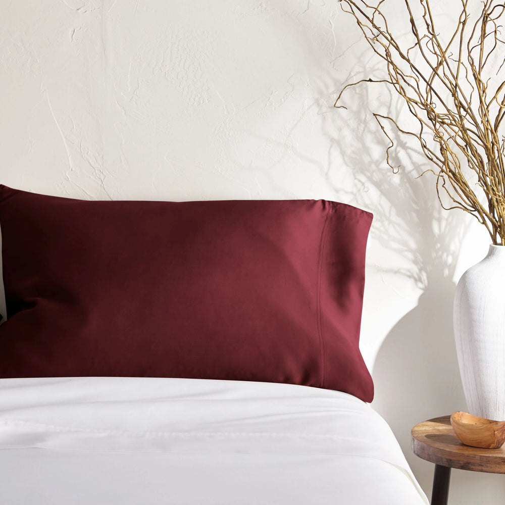 ruby red bamboo pillowcase on a ruby red bed from the Signature Collection, styled with vase decor and natural light