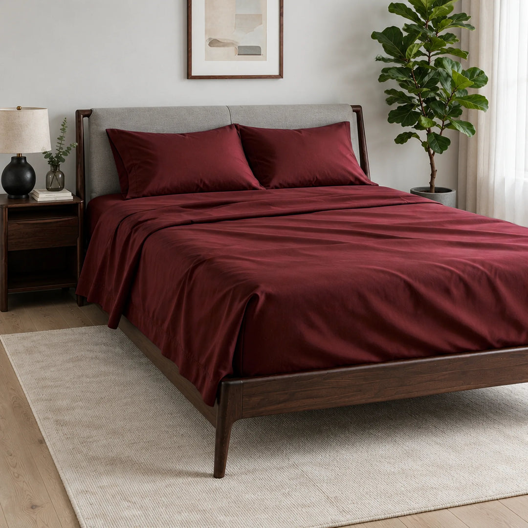 ruby red bamboo viscose sateen sheet set on a dark walnut bed with a light grey upholstered headboard in a bright bedroom