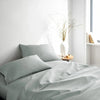 silver bamboo bed sheets with sateen weave from the Signature Collection, three-quarter angle showing natural folds and soft lighting from nearby window