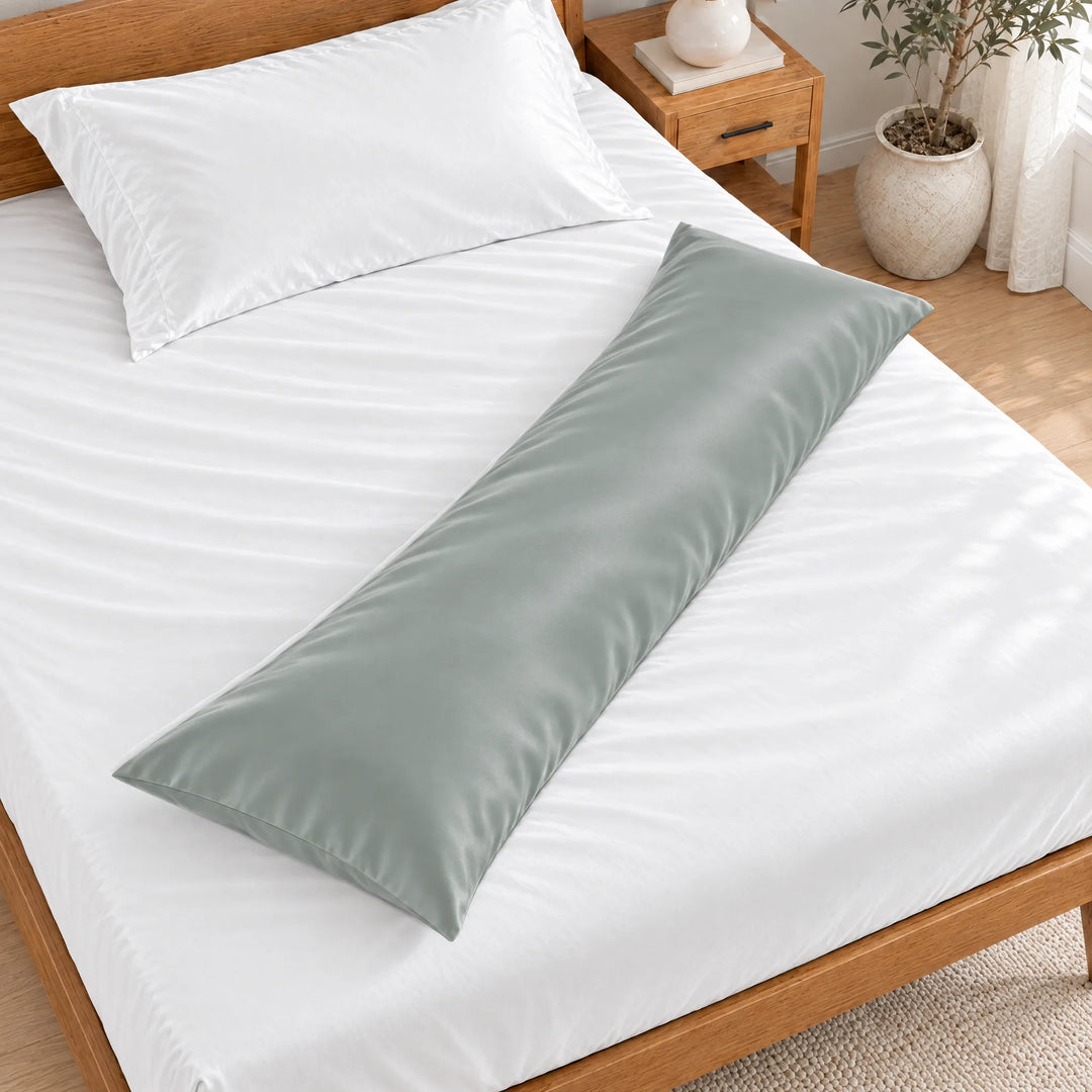 Silver bamboo viscose sateen body pillowcase lying diagonally across a made bed, overhead view in a bright bedroom with a honey bamboo bed