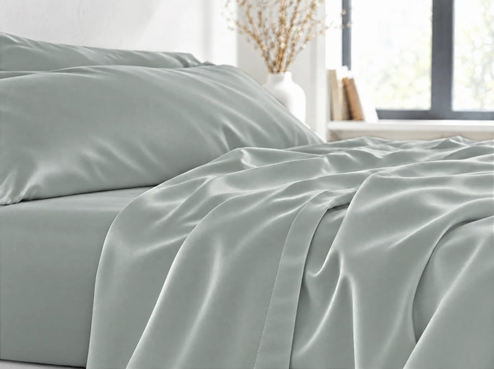 Silver bamboo viscose flat sheet close-up billowing over the mattress edge in relaxed sateen folds