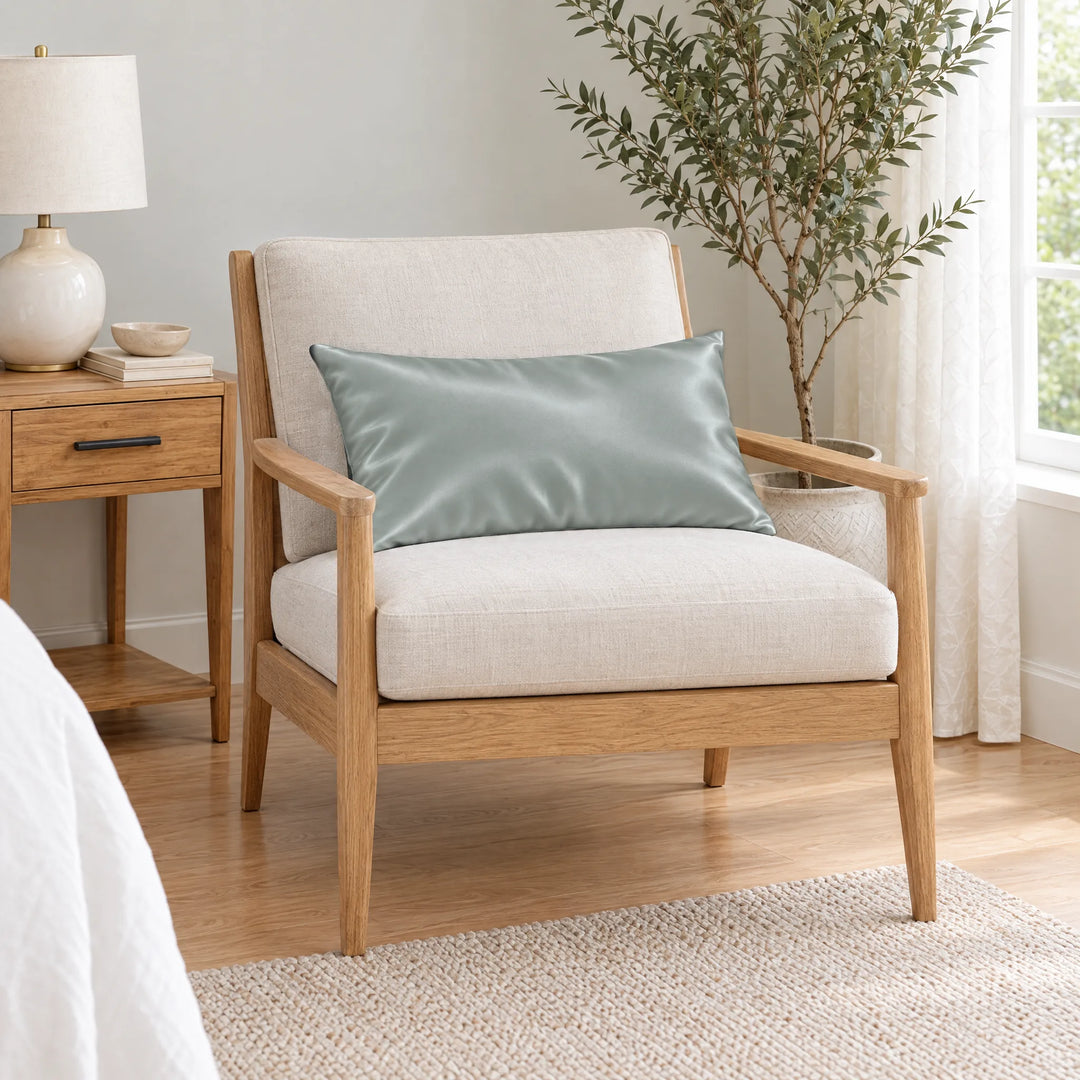 Silver bamboo viscose sateen lumbar pillowcase on a light oak armchair beside a nightstand and olive tree