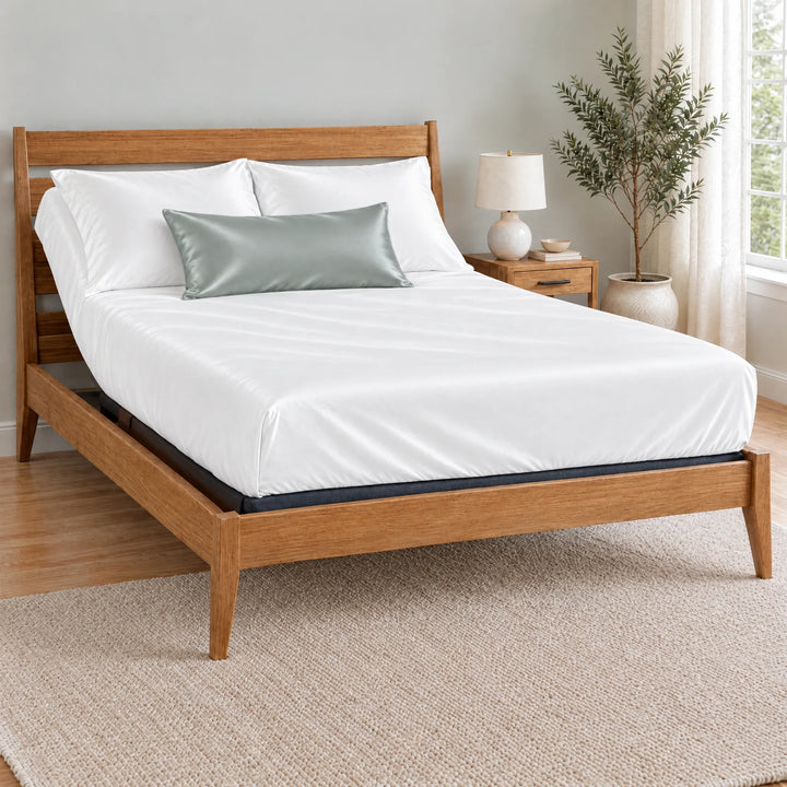 Silver bamboo viscose sateen lumbar pillowcase on a made bed in front of white pillows in a light oak bedroom with an olive tree
