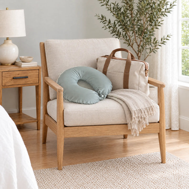 Silver bamboo viscose sateen neck pillowcase on an oak armchair beside a linen travel tote and throw