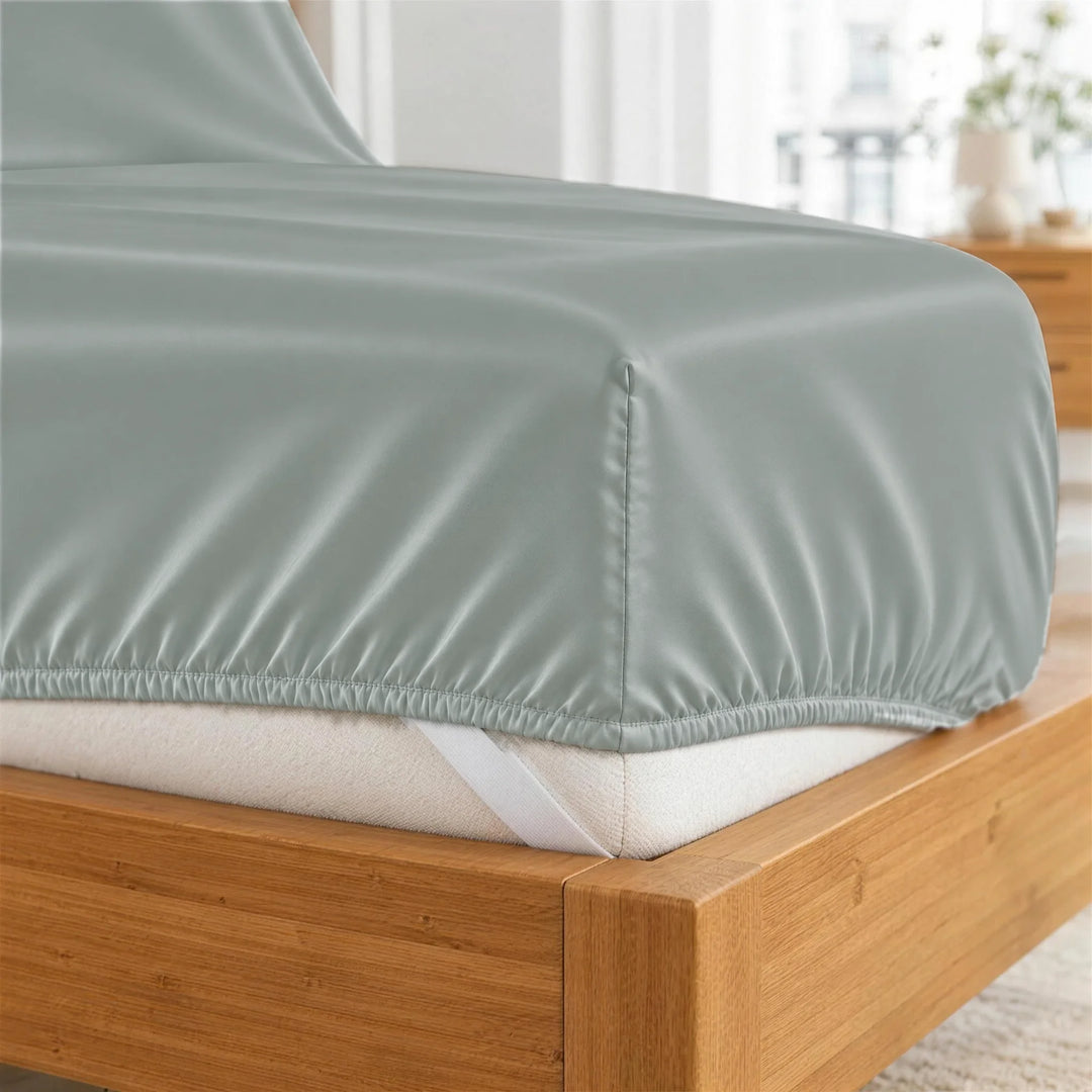 Silver bamboo viscose fitted sheet deep-pocket corner close-up with all-around elastic and a corner strap, from the sheet set