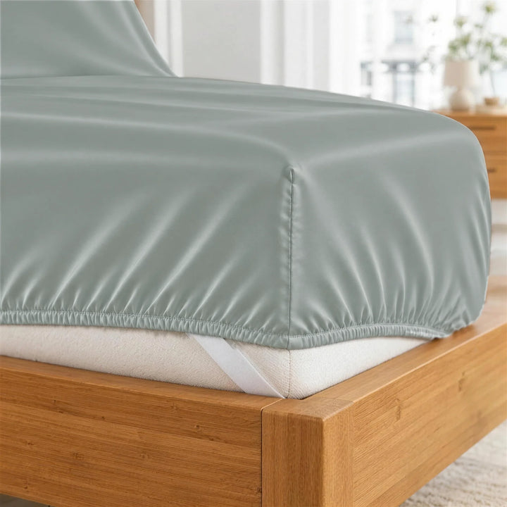 Silver bamboo viscose fitted sheet deep-pocket corner close-up with all-around elastic and a corner strap, from the sheet set