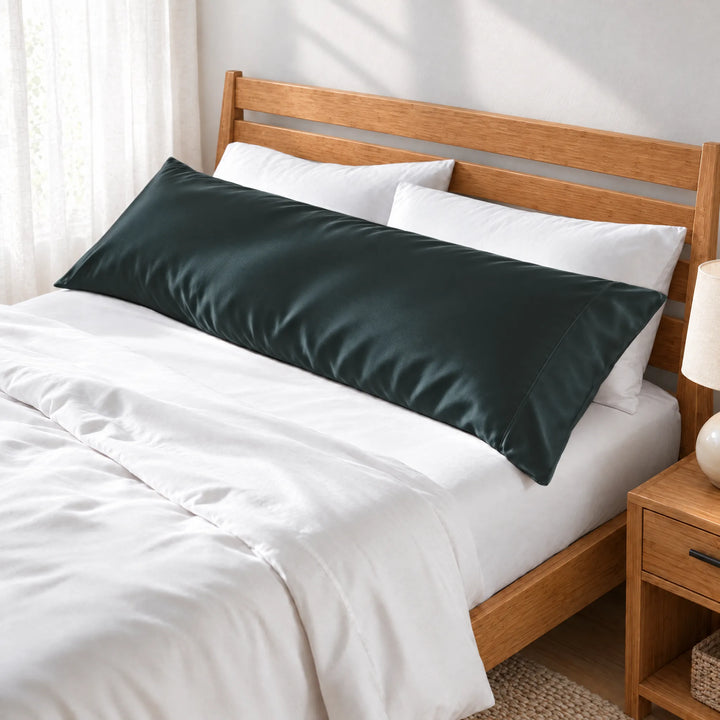 Slate bamboo viscose sateen body pillowcase along the headboard of a made bed, three-quarter view from the foot of the bed