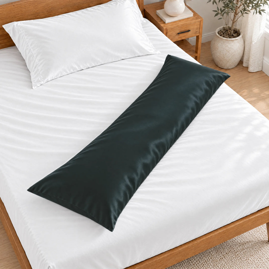 Slate bamboo viscose sateen body pillowcase lying diagonally across a made bed, overhead view in a bright bedroom with a honey bamboo bed