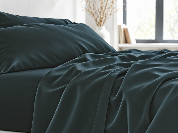 Slate bamboo viscose flat sheet close-up billowing over the mattress edge in relaxed sateen folds