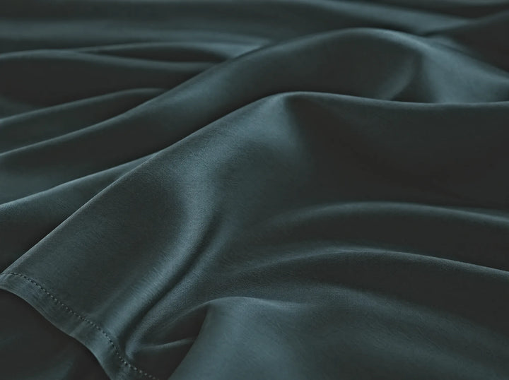 Slate bamboo viscose flat sheet macro close-up of smooth silky sateen folds and a stitched hem