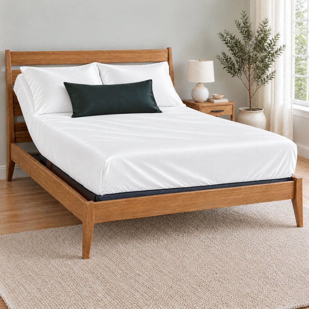 Slate bamboo viscose sateen lumbar pillowcase on a made bed in front of white pillows in a light oak bedroom with an olive tree