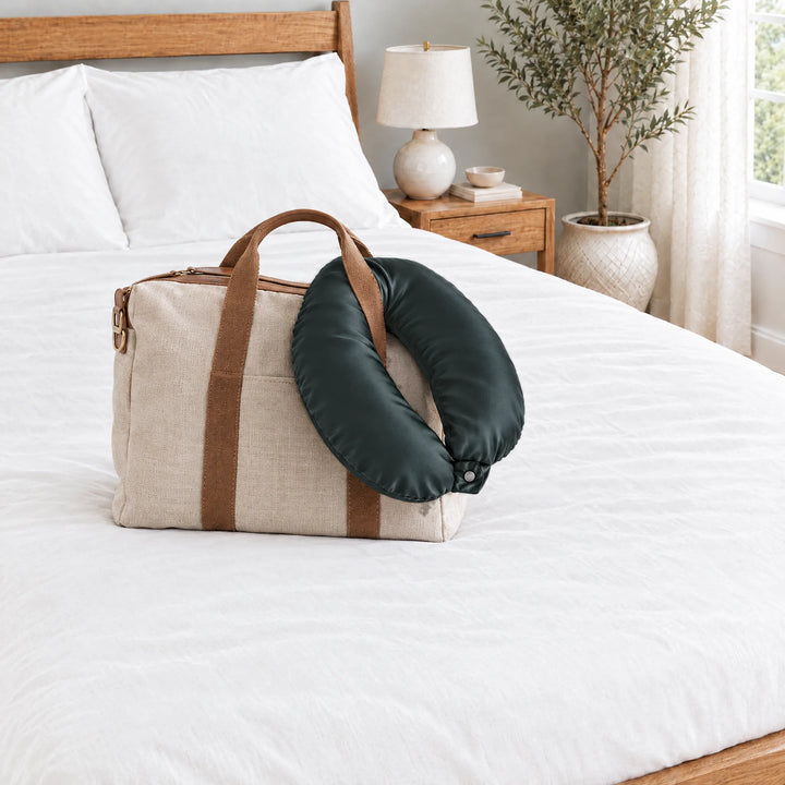Slate bamboo viscose sateen neck pillowcase hanging from a linen tote handle on a made bed