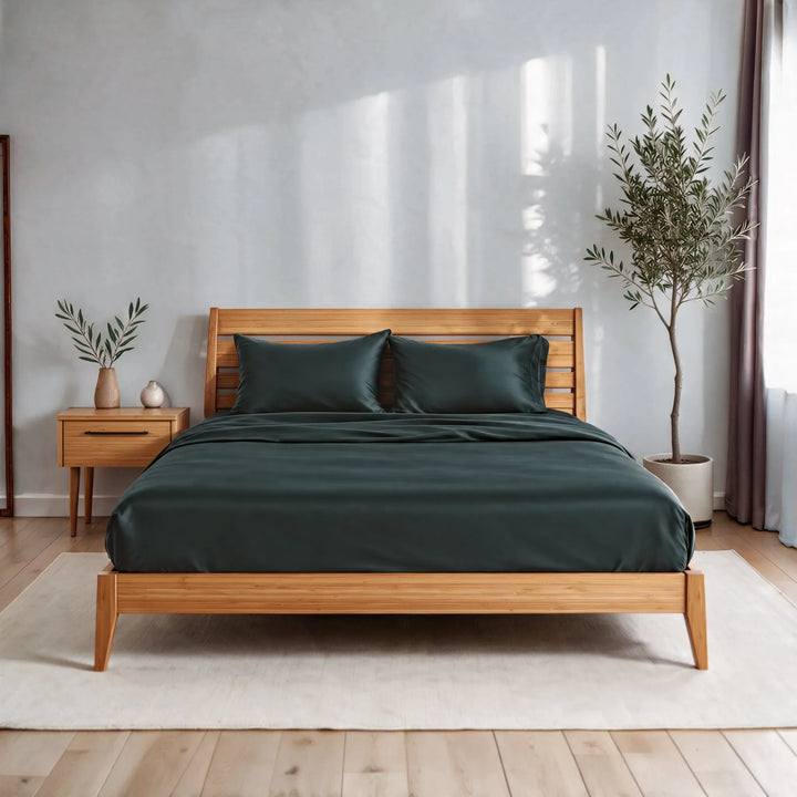 Slate bamboo viscose sateen sheet set on a caramelized bamboo bed frame in a bright bedroom with a cream rug and olive tree