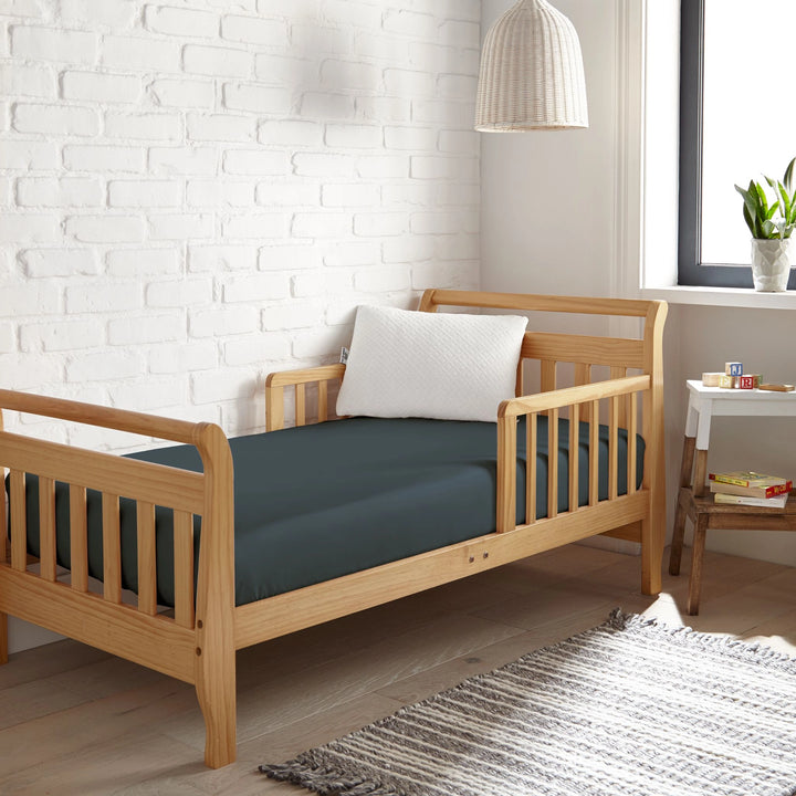 slate bamboo toddler fitted sheet from the Signature Collection, styled in a wooden toddler bed with white pillow and modern nursery decor
