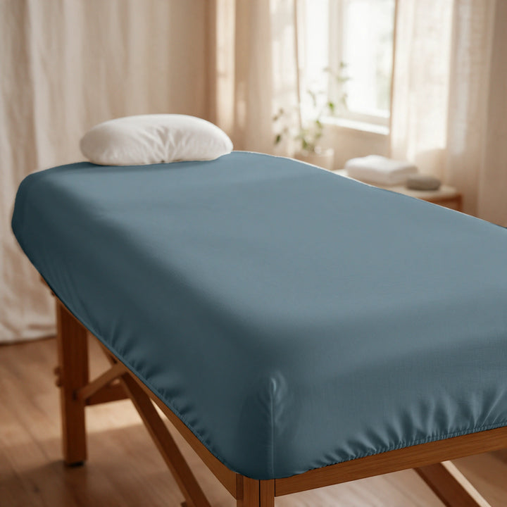 Slate cooling bamboo spa fitted sheet stretched snugly over a professional treatment table, elasticized corners, in a sunlit spa room, Signature Collection