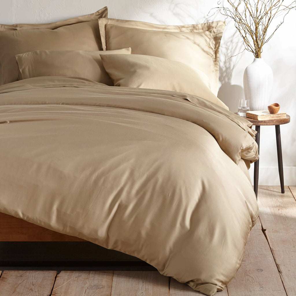 taupe bamboo sateen bedding set with pillowcases and duvet on king bed, styled in minimal bedroom with rustic wood floors and ceramic vase decor