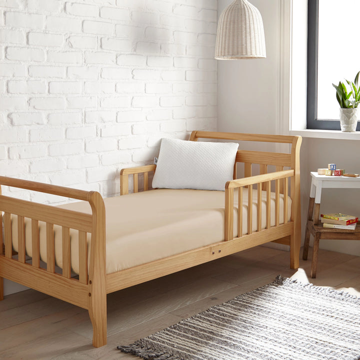 taupe bamboo toddler fitted sheet from the Signature Collection, styled in a wooden toddler bed with white pillow and modern nursery decor