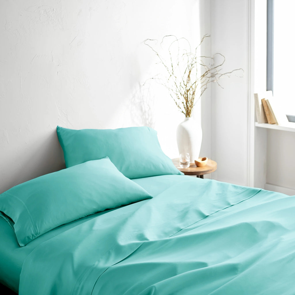 tiffany blue bamboo bed sheets with sateen weave from the Signature Collection, three-quarter angle showing natural folds and soft lighting from nearby window