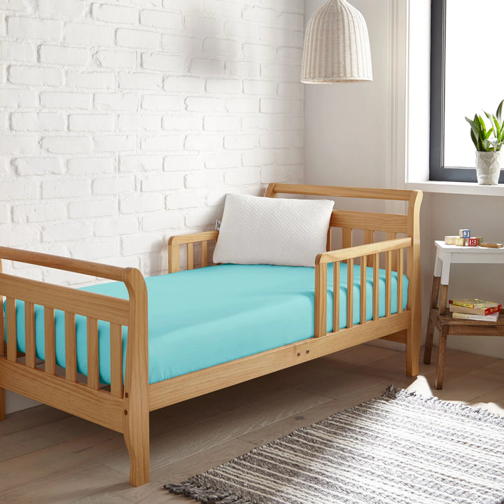 tiffany blue bamboo toddler fitted sheet from the Signature Collection, styled in a wooden toddler bed with tiffany blue pillow and modern nursery decor