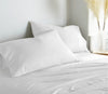 white bamboo bed sheets with sateen weave from the Signature Collection, three-quarter angle showing natural folds and soft lighting from nearby window