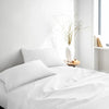 white bamboo bed sheets with sateen weave from the Signature Collection, three-quarter angle showing natural folds and soft lighting from nearby window