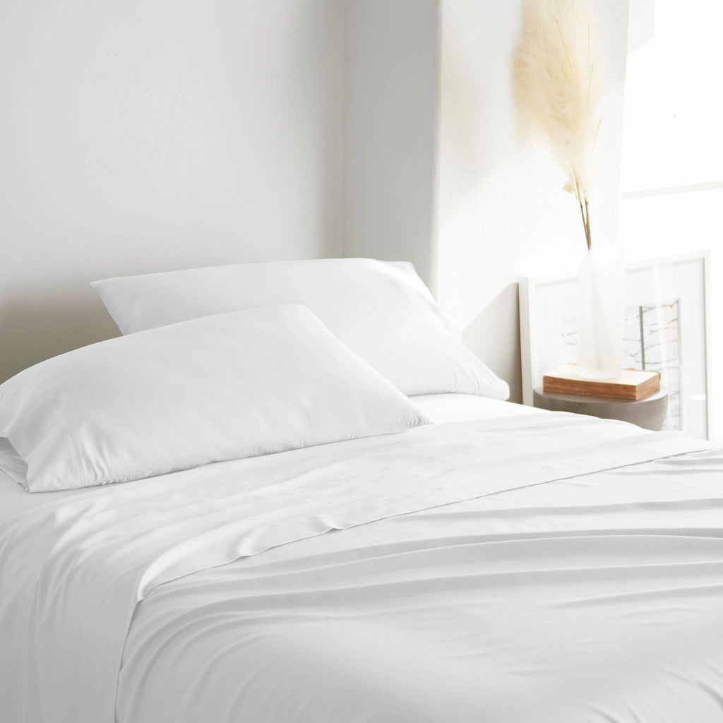 white bamboo bed sheets with sateen weave from the Signature Collection, three-quarter angle showing natural folds and soft lighting from nearby window