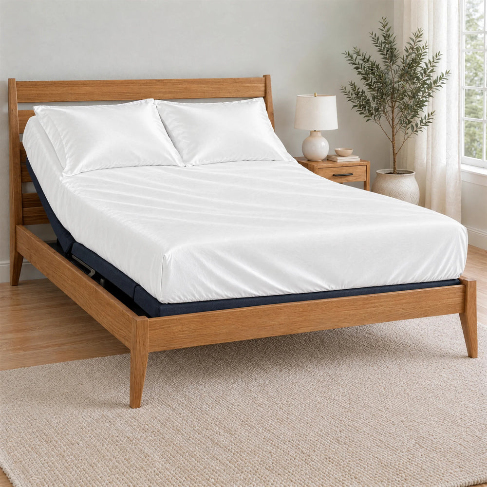 White bamboo viscose Signature fitted sheet on a made bed with a bamboo frame and nightstand in a bright bedroom