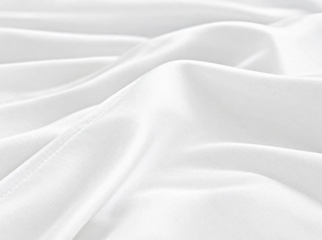 White bamboo viscose flat sheet macro close-up of smooth silky sateen folds and a stitched hem