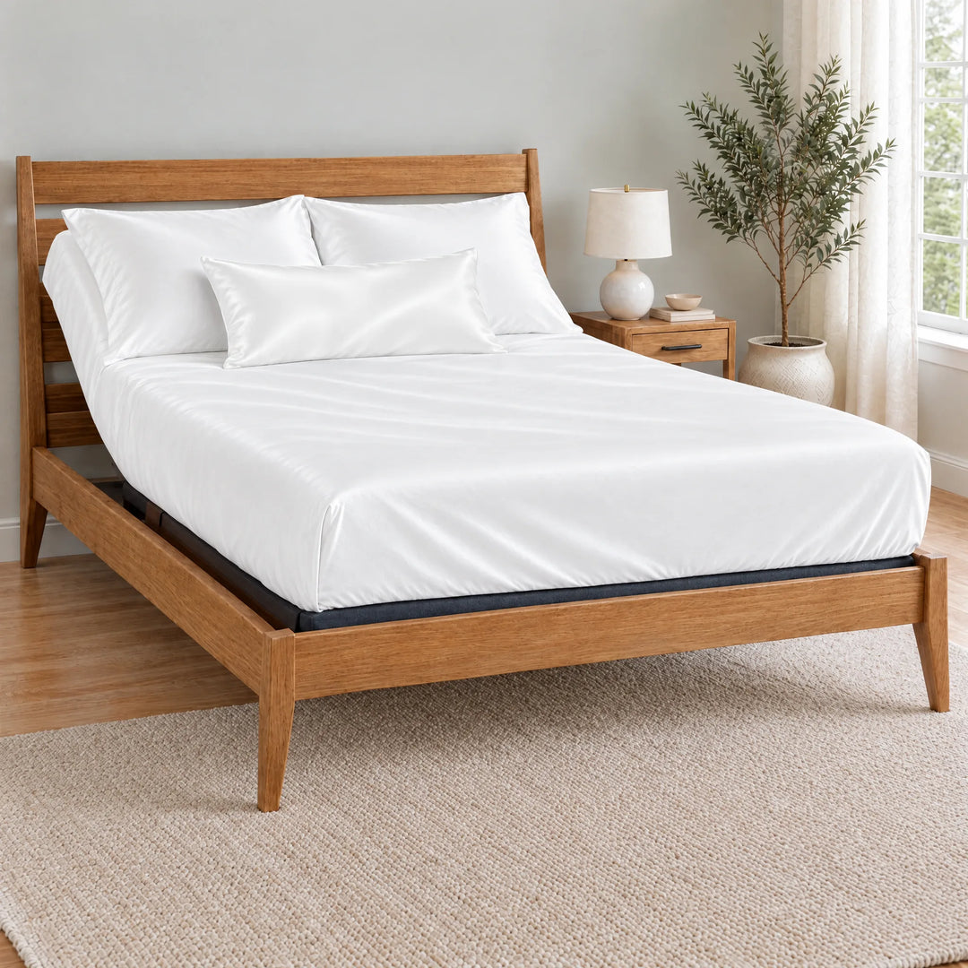 White bamboo viscose sateen lumbar pillowcase on a made bed in front of white pillows in a light oak bedroom with an olive tree