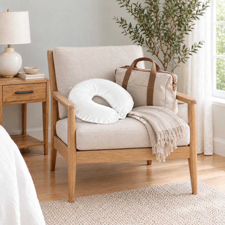 White bamboo viscose sateen neck pillowcase on an oak armchair beside a linen travel tote and throw