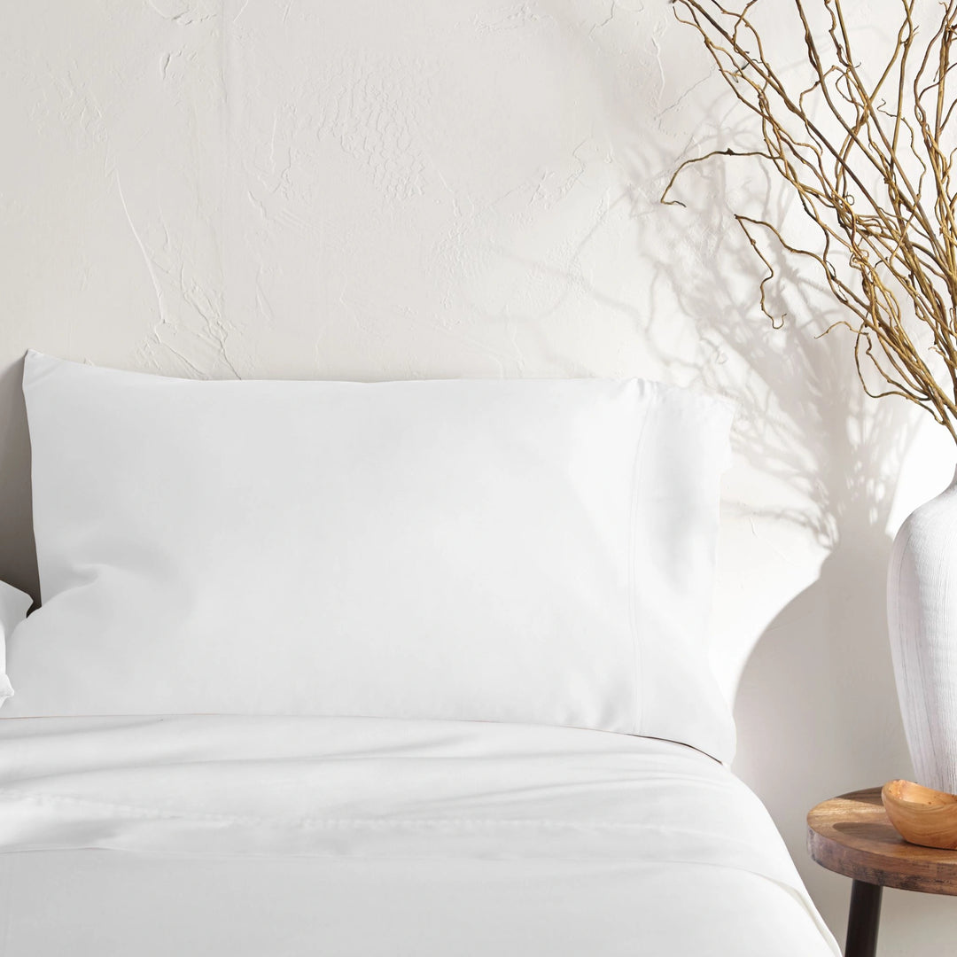 white bamboo pillowcase on a white bed from the Signature Collection, styled with vase decor and natural light