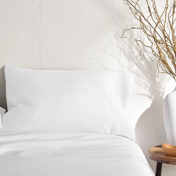 white bamboo pillowcase on a white bed from the Signature Collection, styled with vase decor and natural light