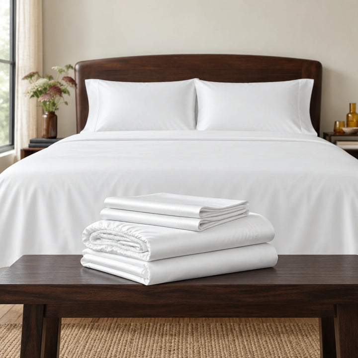 white bamboo viscose sheet set folded on a walnut bench: flat sheet, fitted sheet and pillowcases