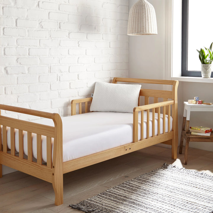 white bamboo toddler fitted sheet from the Signature Collection, styled in a wooden toddler bed with white pillow and modern nursery decor
