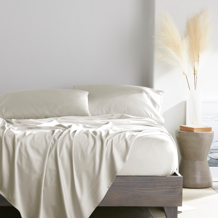 Cream bamboo bed sheets with sateen weave from the Premium Collection, shown from the foot of the bed with a draped flat sheet and matching pillowcases
