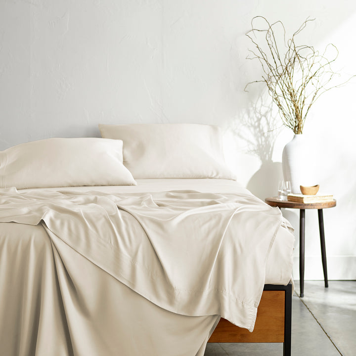 ivory bamboo bed sheets with sateen weave from the Signature Collection, shown from the foot of the bed with a draped flat sheet and matching pillowcases