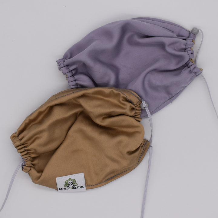 Reversible fabric face mask in lavender and beige, with adjustable ear loops and a brand label for a comfortable, secure fit