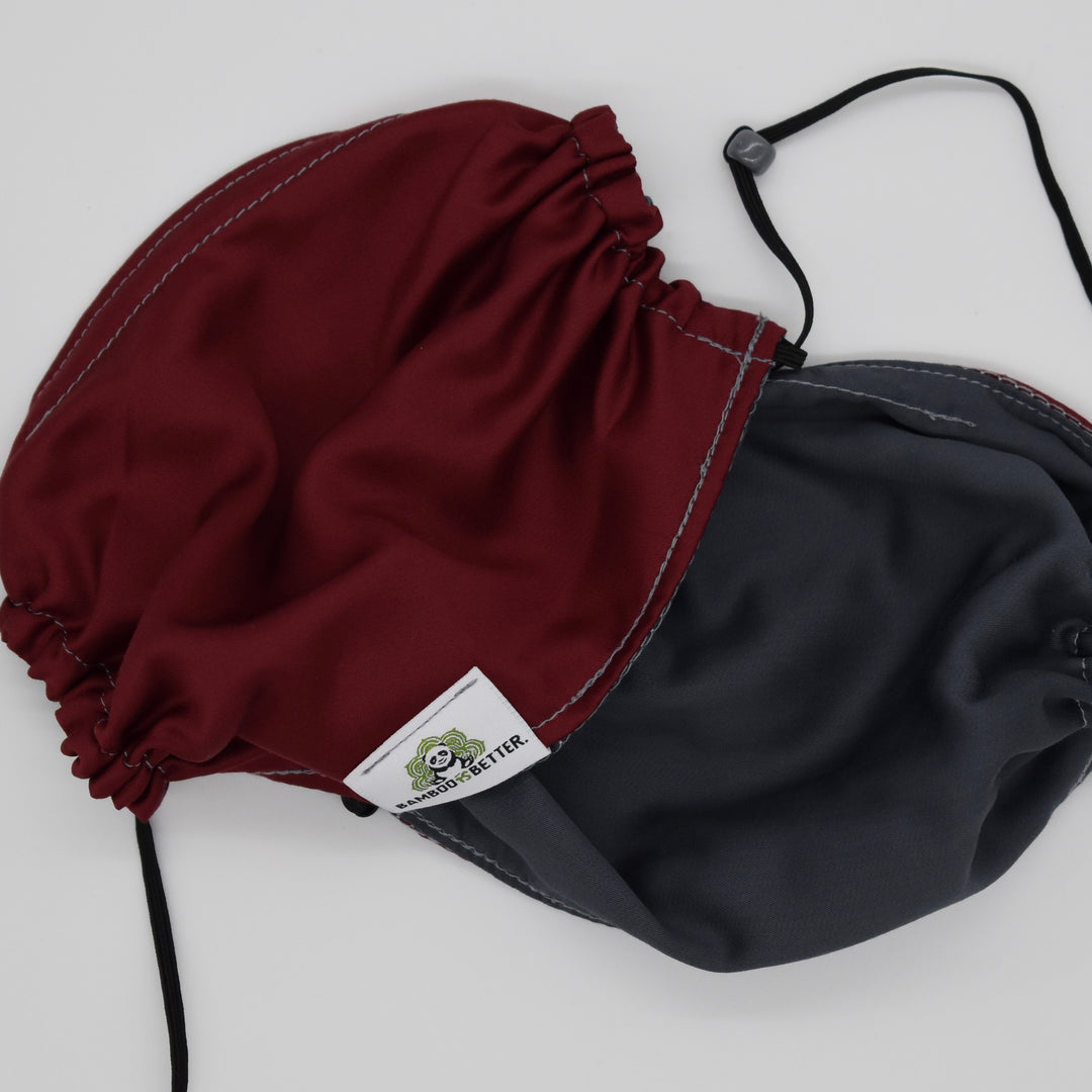Reversible fabric face mask in maroon and gray, featuring adjustable ear loops and a brand label for a comfortable fit