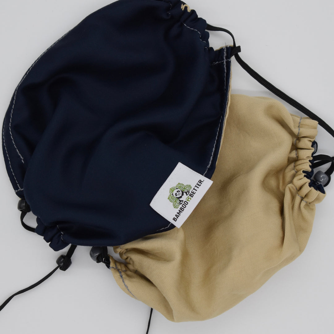 Reversible fabric face mask in navy blue and beige, featuring adjustable ear loops and a brand label for comfort and a secure fit.