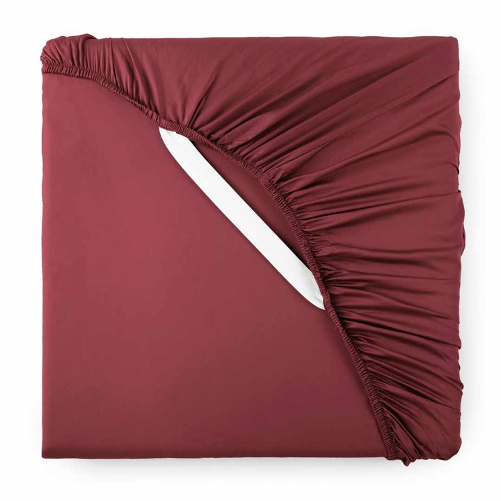 ruby red bamboo sateen fitted sheet corner with ruby red elastic strap, showing snug fit and smooth fabric texture