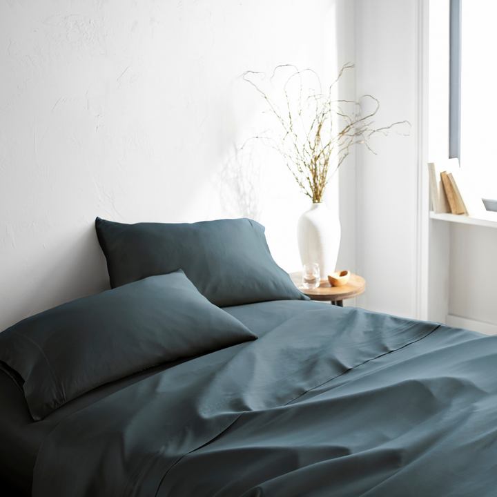 slate bamboo bed sheets with sateen weave from the Signature Collection, three-quarter angle showing natural folds and soft lighting from nearby window
